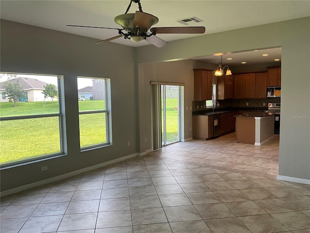 kitchen featuring sink, hanging light fixtures, backsplash, appliances with stainless steel finishes, and light tile patterned floors