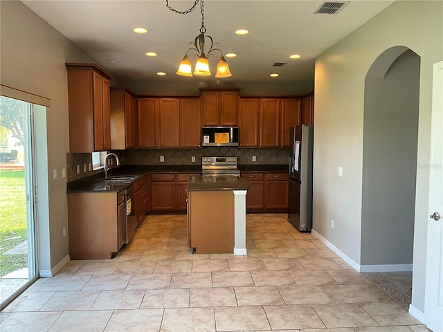 kitchen with hanging light fixtures, tasteful backsplash, stainless steel appliances, a center island, and sink