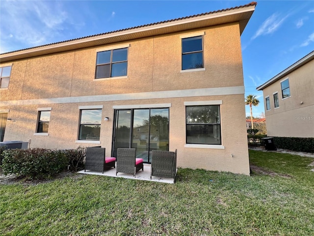 rear view of property featuring a lawn and a patio