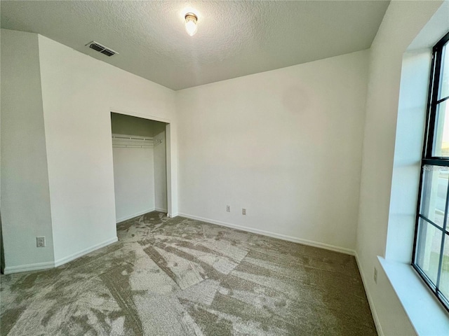 unfurnished bedroom with a textured ceiling, light colored carpet, and a closet