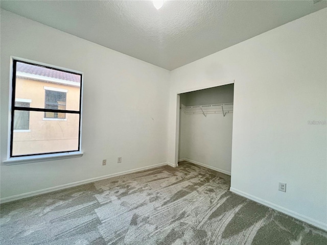 unfurnished bedroom with light colored carpet, a textured ceiling, and a closet