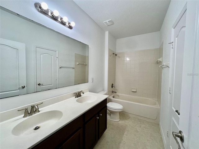 full bathroom with vanity, tiled shower / bath combo, toilet, and a textured ceiling