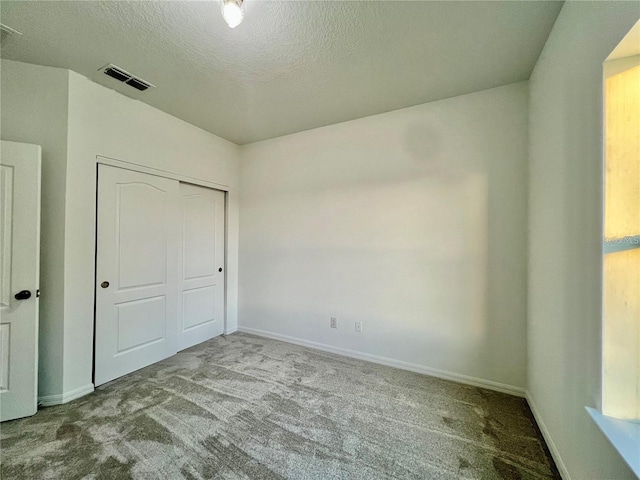 unfurnished bedroom with light colored carpet, a textured ceiling, and a closet