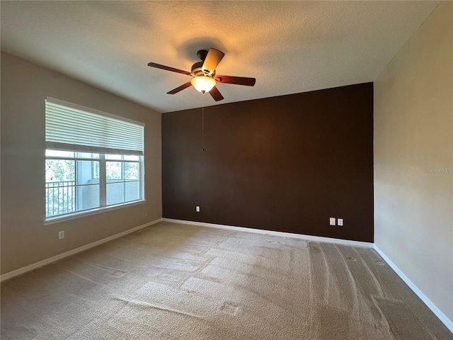 empty room featuring a textured ceiling, light carpet, and ceiling fan