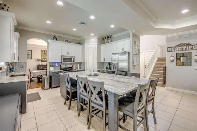 dining area featuring ornamental molding, light tile patterned floors, and sink