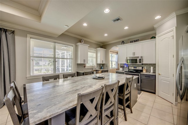 kitchen featuring ornamental molding, stainless steel appliances, white cabinets, and a center island