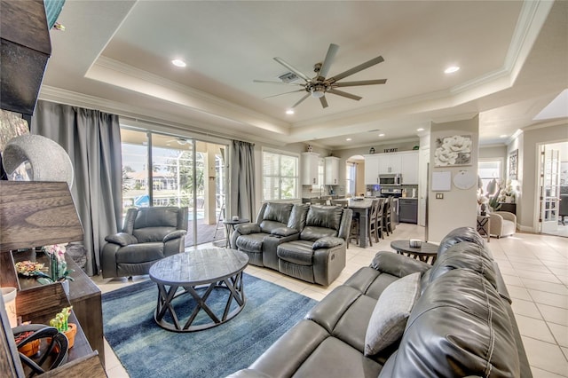 tiled living room with ornamental molding, ceiling fan, and a raised ceiling