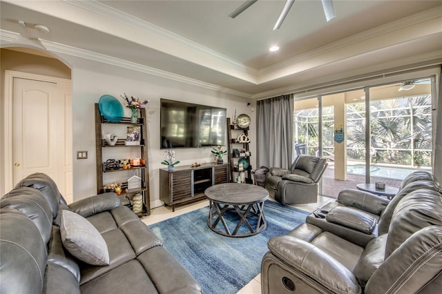 living room featuring ceiling fan, a tray ceiling, crown molding, and light tile patterned floors