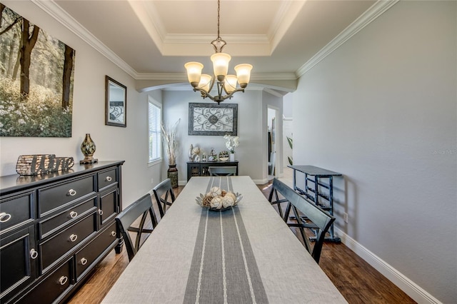 dining space featuring a tray ceiling, dark hardwood / wood-style floors, ornamental molding, and a chandelier