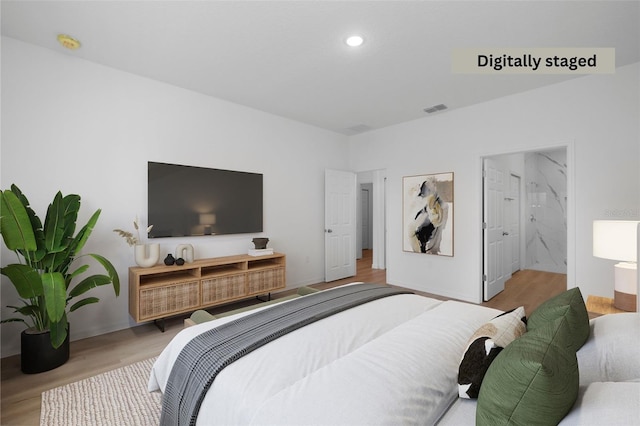 bedroom featuring ensuite bathroom and light hardwood / wood-style floors