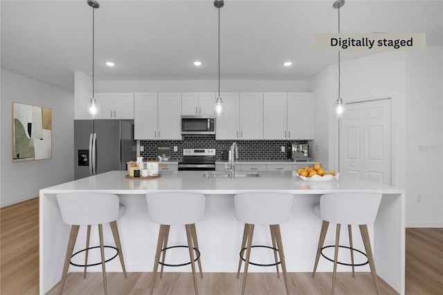 kitchen with pendant lighting, a large island with sink, and stainless steel appliances