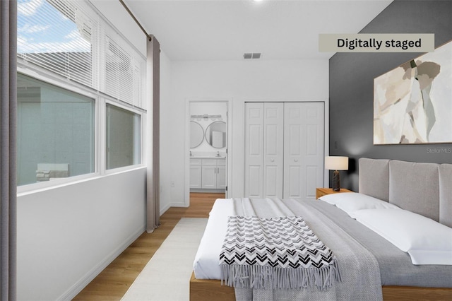 bedroom with a closet, ensuite bath, and light wood-type flooring