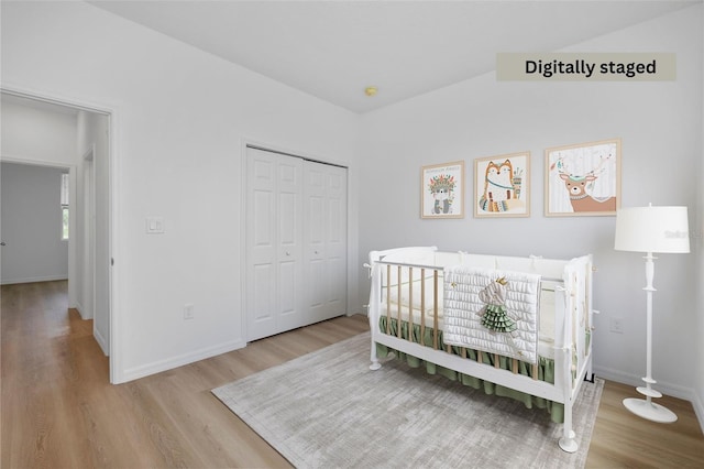 bedroom featuring light hardwood / wood-style floors, a nursery area, and a closet