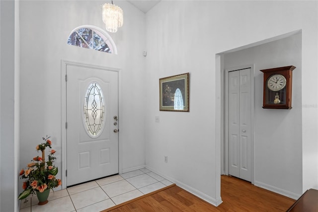 entryway featuring a notable chandelier, light hardwood / wood-style floors, and a high ceiling