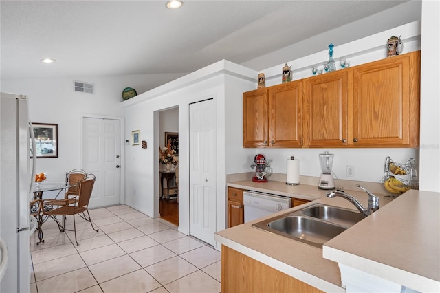 kitchen featuring lofted ceiling, sink, light tile patterned floors, and white appliances