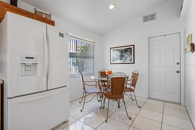 dining area with light tile patterned floors and vaulted ceiling