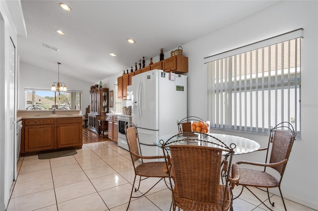 kitchen with stainless steel appliances, an inviting chandelier, pendant lighting, vaulted ceiling, and light tile patterned flooring