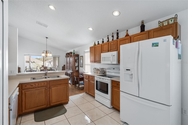 kitchen with sink, an inviting chandelier, pendant lighting, lofted ceiling, and white appliances