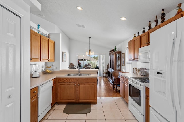 kitchen with light tile patterned floors, white appliances, decorative light fixtures, and vaulted ceiling