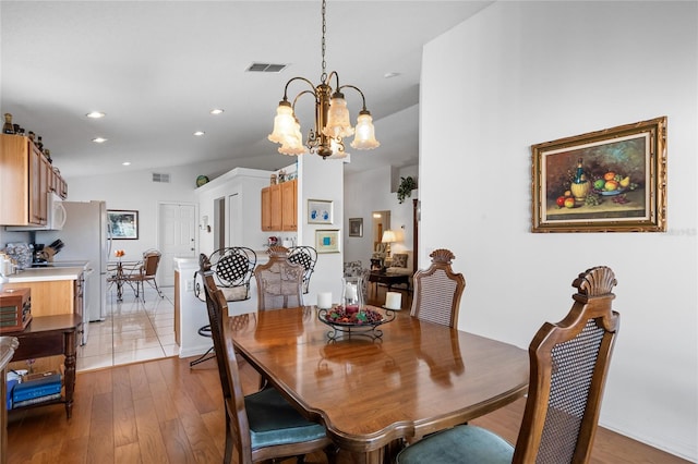 dining room with light hardwood / wood-style flooring and an inviting chandelier