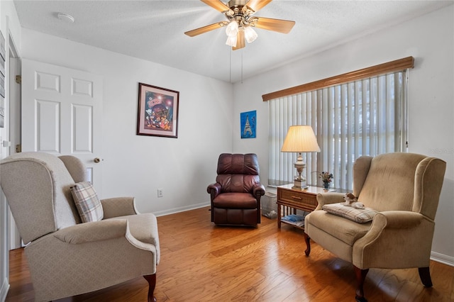 sitting room with ceiling fan, light hardwood / wood-style floors, and a textured ceiling