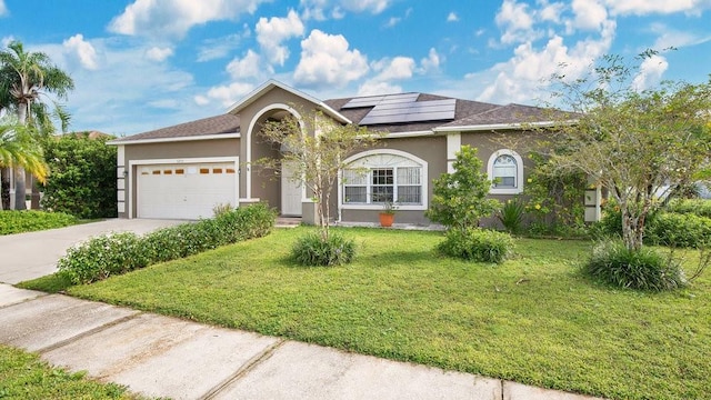 view of front facade featuring a garage, solar panels, and a front yard