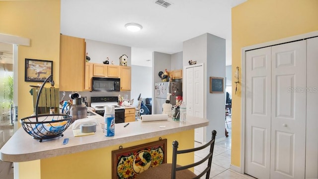 kitchen with kitchen peninsula, white electric range, light tile patterned floors, light brown cabinetry, and stainless steel fridge