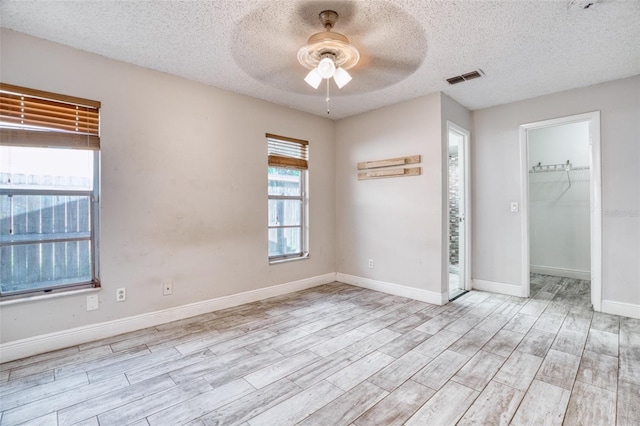 unfurnished bedroom featuring a closet, a textured ceiling, light wood-type flooring, and ceiling fan