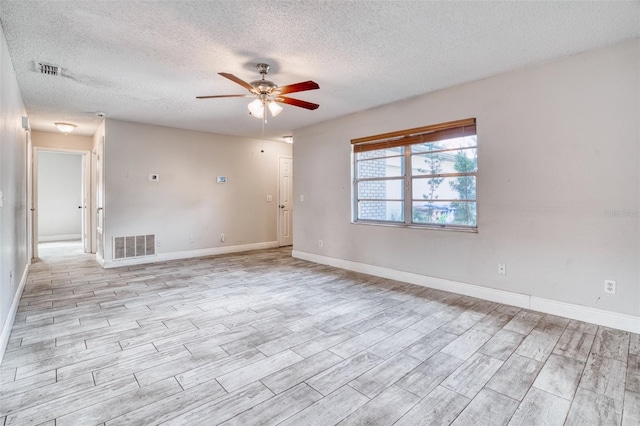 empty room featuring a textured ceiling, light hardwood / wood-style floors, and ceiling fan