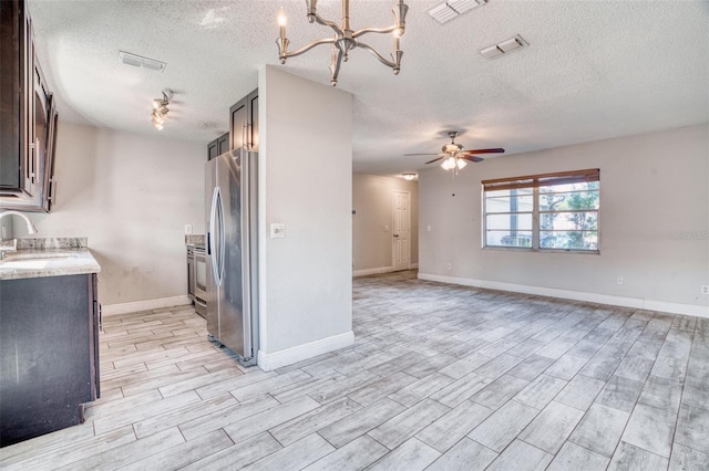 kitchen with light hardwood / wood-style floors, a textured ceiling, stainless steel appliances, and dark brown cabinets