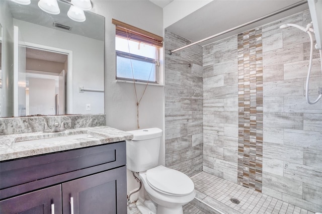 bathroom with vanity, a tile shower, and toilet