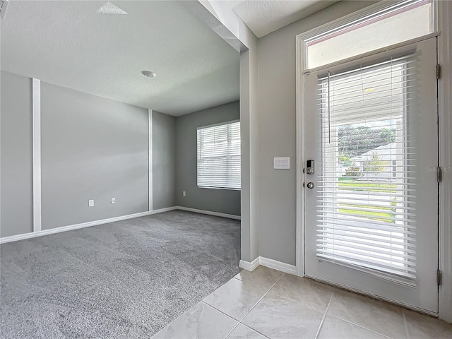 carpeted entryway with a textured ceiling