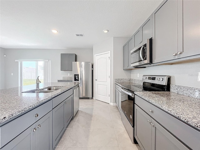 kitchen with light stone counters, sink, a textured ceiling, gray cabinets, and appliances with stainless steel finishes