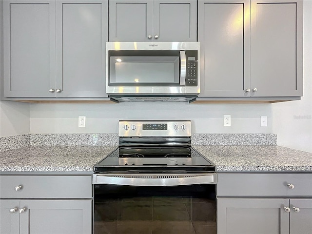 kitchen featuring light stone countertops, appliances with stainless steel finishes, and gray cabinetry