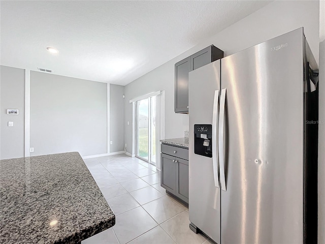 kitchen featuring dark stone countertops, gray cabinets, and stainless steel fridge