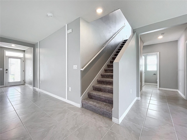 stairway with a healthy amount of sunlight and tile patterned flooring