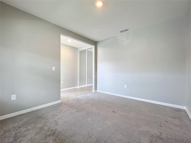 spare room featuring light carpet and a textured ceiling