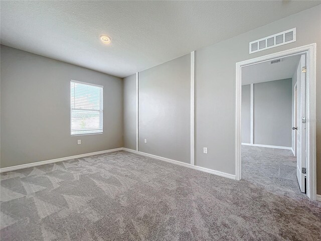 carpeted empty room with a textured ceiling