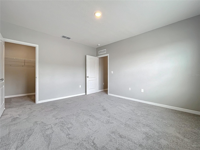 unfurnished bedroom featuring light colored carpet, a closet, and a walk in closet