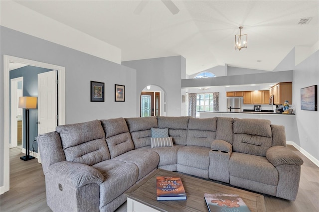 living room with light hardwood / wood-style flooring, high vaulted ceiling, and ceiling fan with notable chandelier