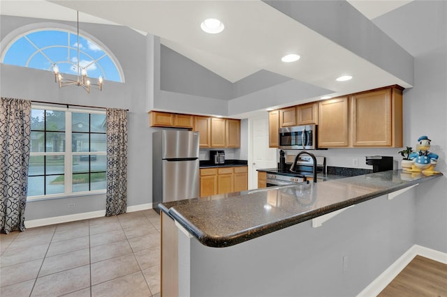 kitchen with kitchen peninsula, light tile patterned floors, a chandelier, pendant lighting, and stainless steel appliances