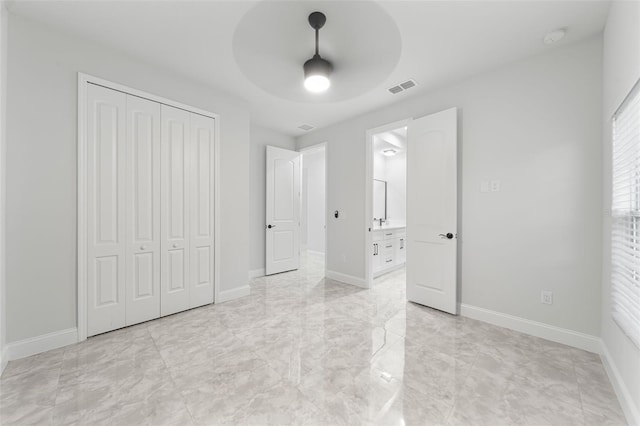 unfurnished bedroom featuring a closet, connected bathroom, and ceiling fan