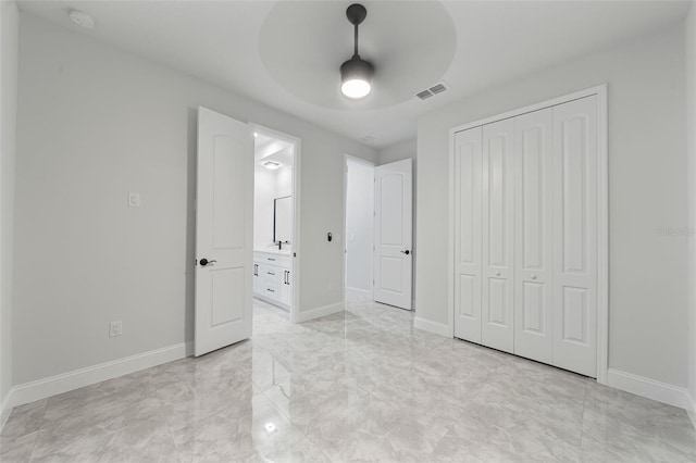 unfurnished bedroom with a closet, ensuite bath, and ceiling fan