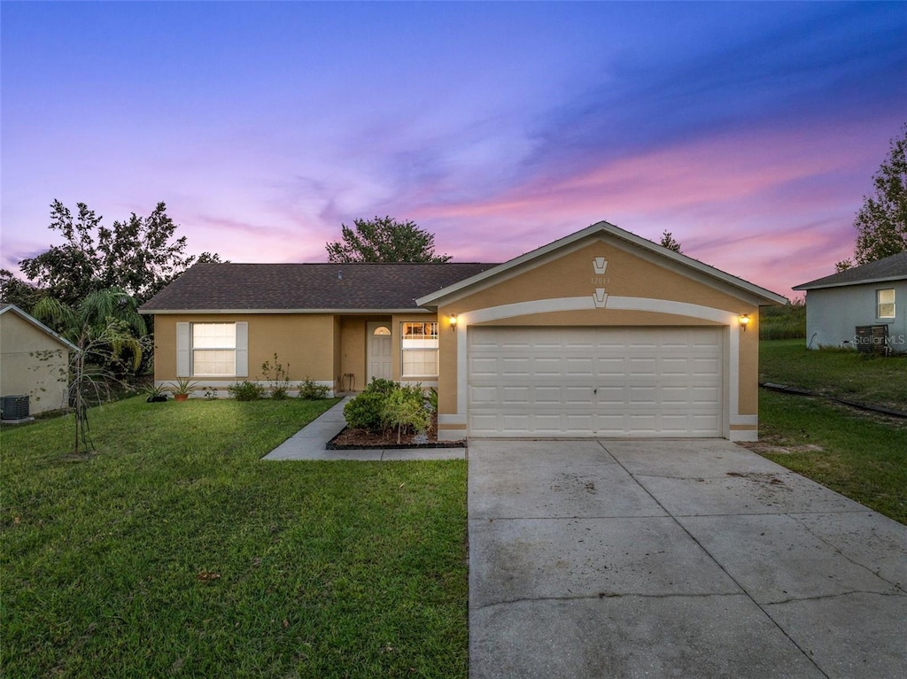 single story home featuring a lawn, cooling unit, and a garage