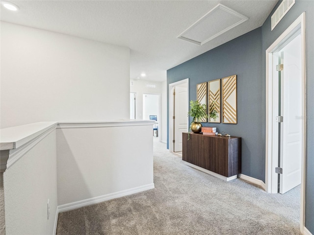 hallway with a textured ceiling and light carpet