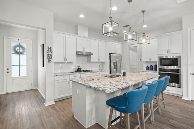 kitchen with white cabinetry, stainless steel appliances, and a center island with sink