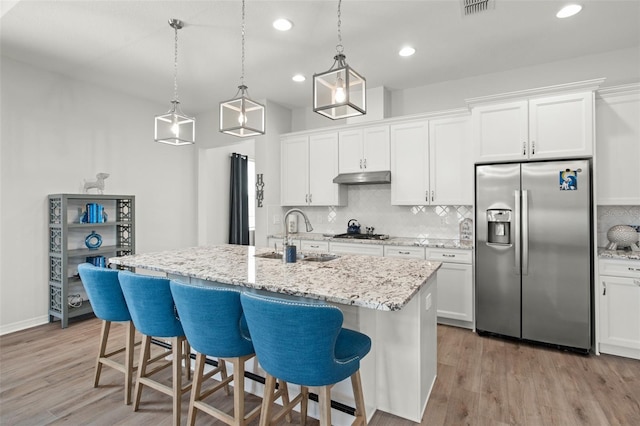 kitchen with a kitchen island with sink, sink, light wood-type flooring, white cabinetry, and appliances with stainless steel finishes