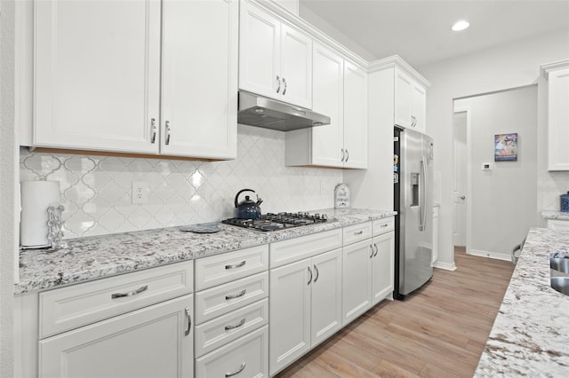 kitchen with decorative backsplash, light hardwood / wood-style flooring, stainless steel appliances, light stone countertops, and white cabinets