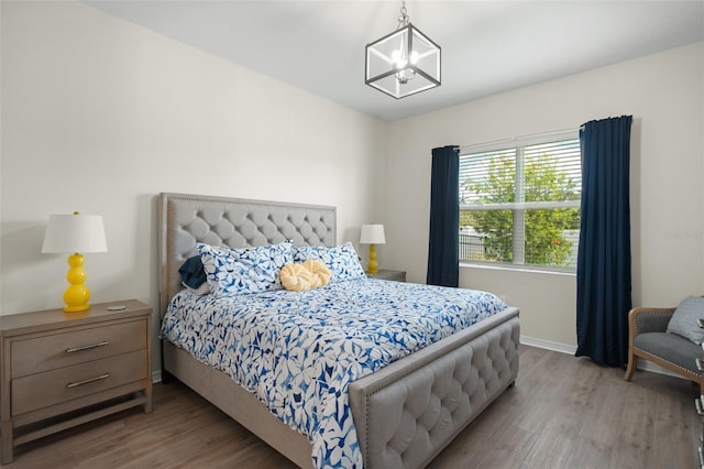 bedroom featuring wood-type flooring and an inviting chandelier