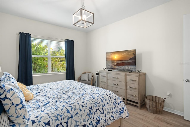 bedroom with light hardwood / wood-style flooring and an inviting chandelier